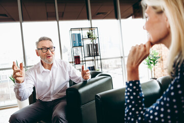 Senior businessman having a collaborative discussion with a colleague in a modern office setting, emphasizing teamwork