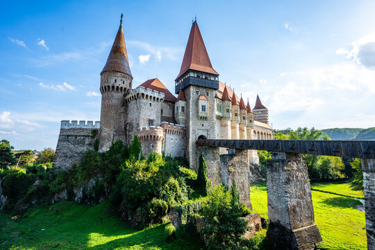 Panoramic View of Corvin Castle in Hunedoara, Romania with Defensive Towers and Elevated Bridge over Lush Green Landscape
