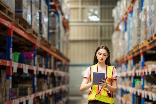 Professional female warehouse worker scans products and updates inventory on tablet. Smart technology for stock control in a distribution center.