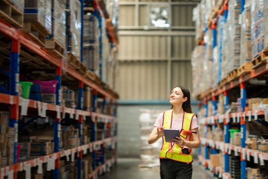 Happy warehouse staff woman using digital tablet and barcode reader to check stock. Modern inventory system and warehouse management in action.