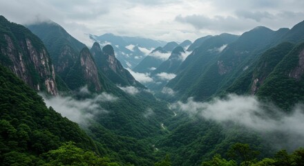 Obraz premium Misty mountain valley, lush greenery, dramatic rock formations. Clouds drift low, creating an ethereal atmosphere