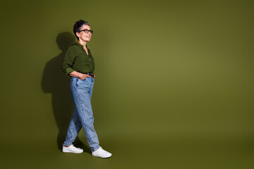 Middle aged woman wearing casual fashion walking confidently with a smile on khaki background expressing stylish charm