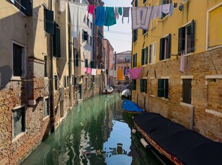 Drying laundry above Rio Del Ghetto water canal in Venice, Italy with boats