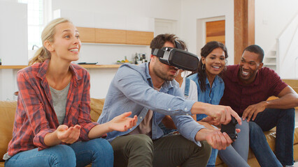 Group Of Multi Cultural Friends Playing Computer Game With Virtual Reality Headset At Home