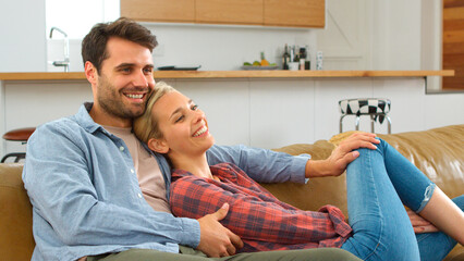 Young Couple Sitting On Couch At Home Watching Television Together