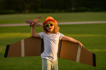 Happy childhood. Pilot aviator child with a toy airplane plays on summer nature. Child playing with plane wings. Concept of dreams and travels.