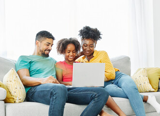 Mother, father and daughter doing homework with laptop at home. Mom, dad and teenage black girl...