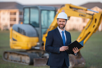 Buider man in suit and hardhat. Construction investor. Business man investor in front of construction site. Successful investor. Handsome man in suit and hardhat at building construction.