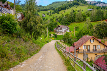 Fototapeta premium Rustic Dirt Road Leading Through a Mountain Village in Moieciu, Brașov County, Romania