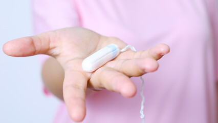 Healthcare professional in pink uniform displaying feminine hygiene product tampon, highlighting menstrual wellness and medical education with confident professional gesture