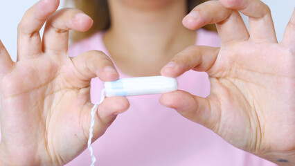 Female hand grasping feminine hygiene product tampon, representing monthly wellness, personal care, and menstrual health management with subtle confidence