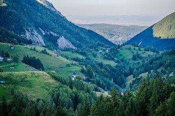 Obraz premium Scenic Mountain Valley with Distant Villages and Forested Slopes in Brașov County, Romania
