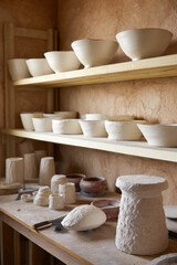 Artisan pottery studio filled with unfinished clay pieces arranged neatly on shelves, showcasing a creative and organized workspace for pottery enthusiasts
