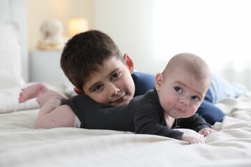 Cute little brothers on bed at home