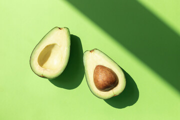 Avocado fruit cut on half on the green table background. Top view	