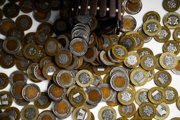 Ghanaian cedi coins in container poured spread on desk surface