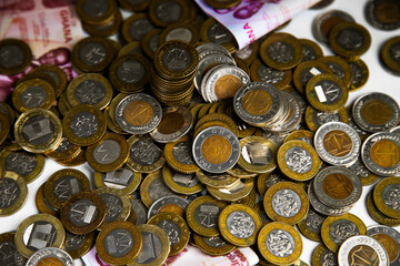 Close up of a lot of Ghanaian cedi coins with few notes spread on desk
