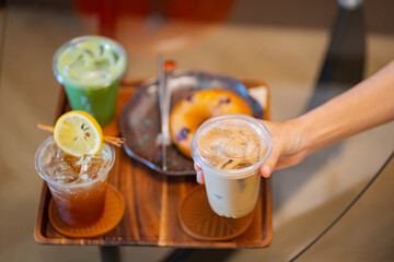 hand of woman holding a take-out iced coffee on black table, from above in flat lay concept.