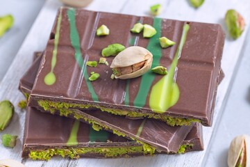 Dubai style milk chocolate bar with pistachio and kadaifi filing, lying on cutting board, horizontal
