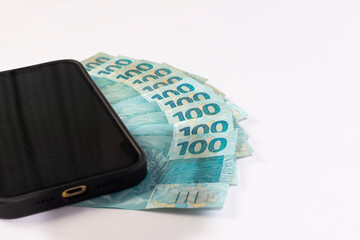 Black Cellphone and Brazilan 100 Reais Banknotes on a white background