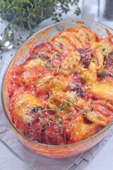 Sweet potato, parsnips and beet root au gratin with thyme and melted cheese, in glass dish, vertical