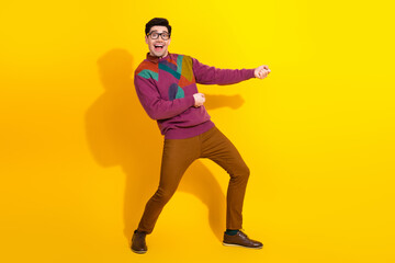 Stylish young man in glasses posing confidently against a vibrant yellow background expressing excitement and fashion.