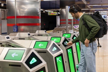 Young man scanning a subway card at fare gate as he heads to work in subway station