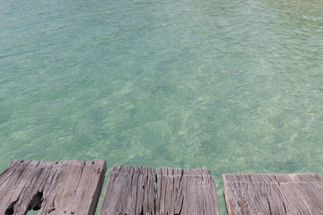 Old wood bridge floor with clear water.
