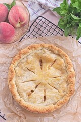 Freshly baked old fashioned deep dish peach pie cooling on baking rack, vertical top view
