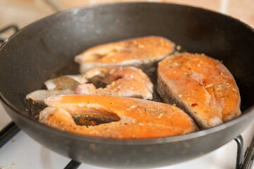 frying black pan with salmon fish close up
