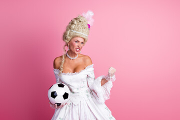 Elegant baroque woman with soccer ball on pink backdrop blending royalty charm and modern concepts