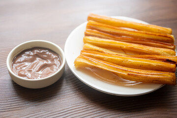 Churros sticks with chocolate sauce on a white plate