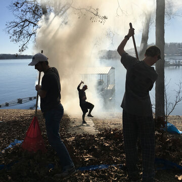 Boys funny pose while raking leaves at lake