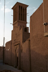 Elegant windcatcher tower rises above the historic adobe skyline of Yazd, Iran, showcasing traditional Persian desert architecture and natural cooling design.