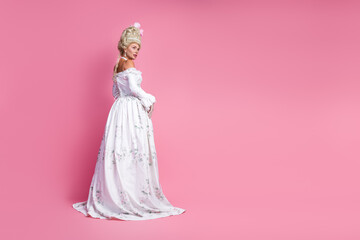 Elegant young lady wearing a baroque white gown in a modern pink setting blending historical...