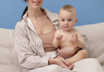 Smiling mother with her little baby on sofa indoors