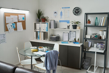 Well-organized medical office featuring a table with cups and snacks, cabinets filled with folders, and a bulletin board with various documents
