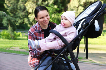 Mother with her cute baby in stroller at park