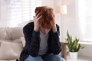 Teen problems. Depressed teenage boy on sofa at home