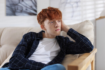 Teen problems. Depressed teenage boy on sofa at home