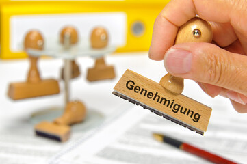 Ein Holzstempel ist beschriftet mit Genehmigung