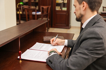 Notary signing document at wooden table in office