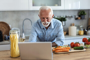 Mature man, laptop and search with recipe tutorial, dinner method or online guide in home. Learning, instructions and senior person in kitchen with healthy ingredients, diet or steps in meal prep