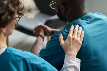 Medical professional comforting a patient by holding their hand in a healthcare environment...