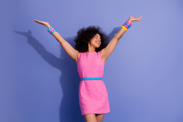 Excited young woman in vibrant pink dress posing joyfully against a violet backdrop, showcasing...