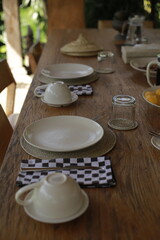 Empty White Plate with Cutlery and Upside-Down Glass on Wooden Table