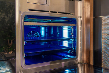 Obraz premium Angled view of stainless wall oven with blue interior lighting