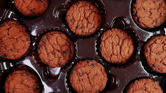 Top view of a tempting sweet chocolate chip cookie with details and texture clearly visible inside a dark plastic packaging. Perfect for advertising or promoting food products.