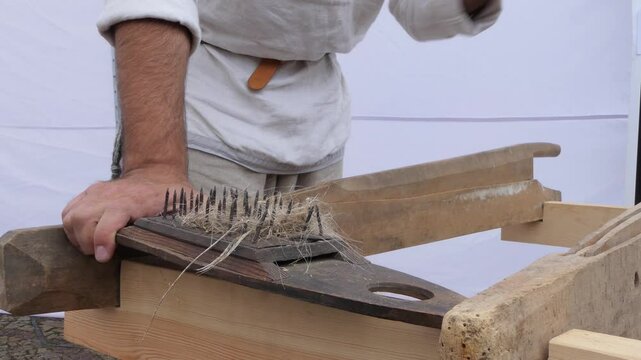 Man is combing flax to remove fiber and get linen thread