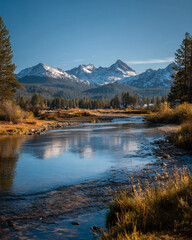 Fototapeta premium A scenic view of a river flowing through a valley with snow capped mountains in the distance on a sunny day